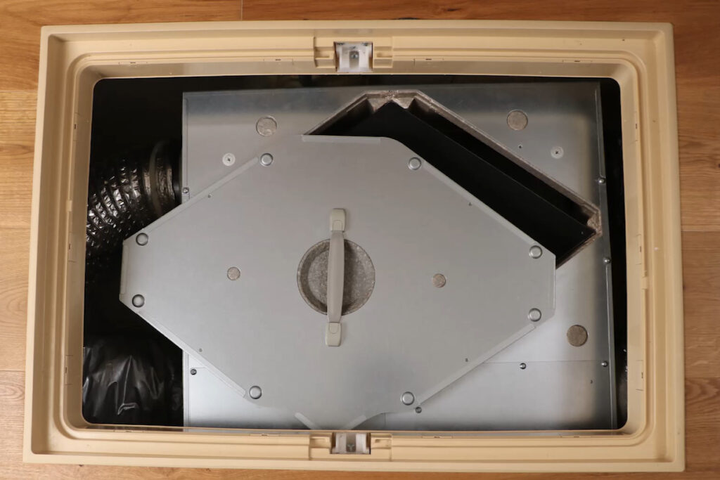 床下点検口の内部に設置された24時間換気システムの本体ユニットと、家全体へ繋がる蛇腹状の配管ダクトの様子