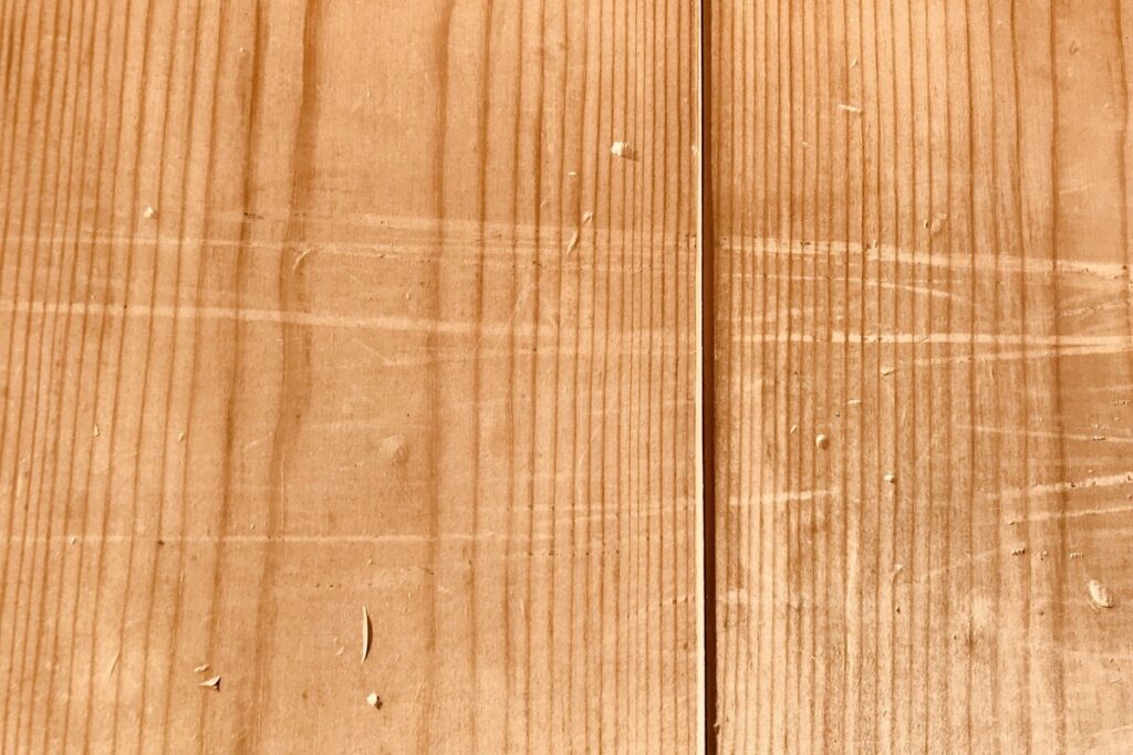 無垢材の表面をアップにした写真。自然素材ならではの力強い木目や、経年変化を感じさせる独特の風合いが伝わるテクスチャ画像。