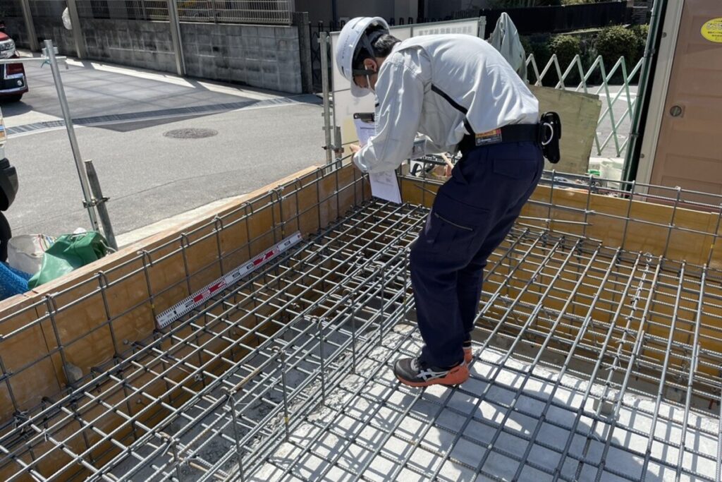 基礎工事の配筋検査において、鉄筋の配置や間隔が設計通りであるか厳密に確認する現場監督。