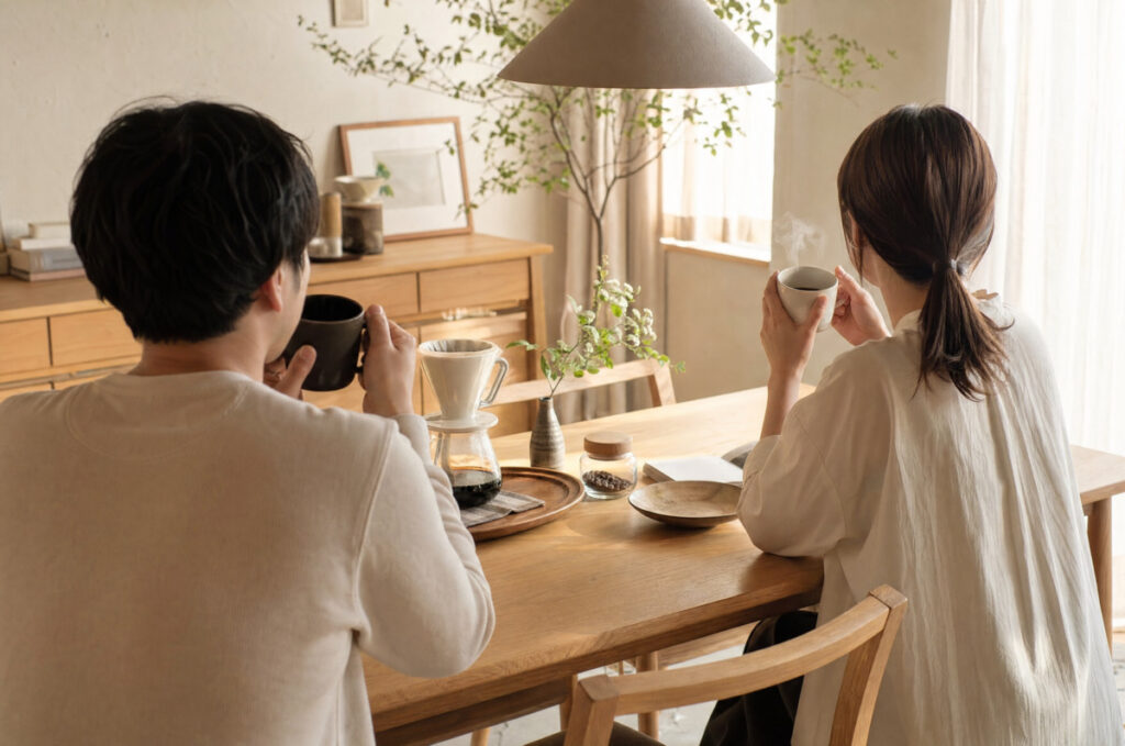 明るいダイニングで、夫婦がコーヒーを飲みながらリラックスした時間を過ごしている様子
