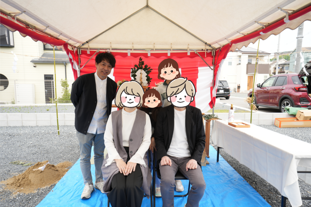 地鎮祭の祭壇が設けられた紅白幕のテント内で、施主様ご家族とスタッフが記念撮影を行っています。