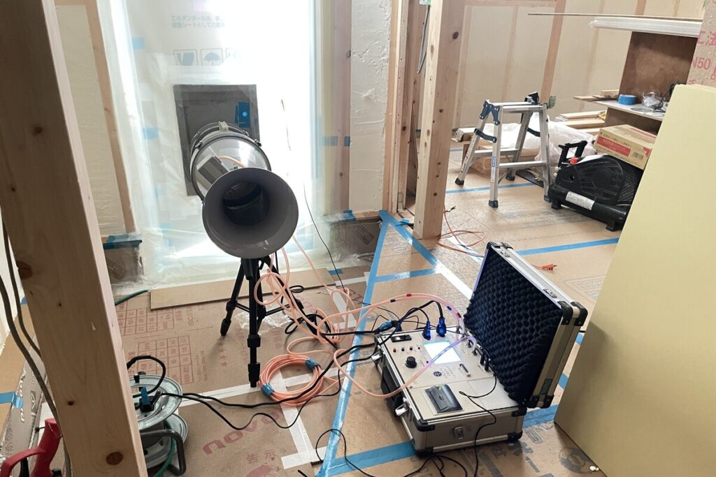 高気密住宅の性能を担保するために、建築現場で専用機器を用いて行われる気密性能試験の様子。