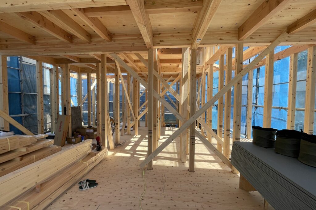 建築中の木造住宅の内部構造。柱や梁、筋交いが規則正しく組まれた堅牢な骨組みを確認できます。
