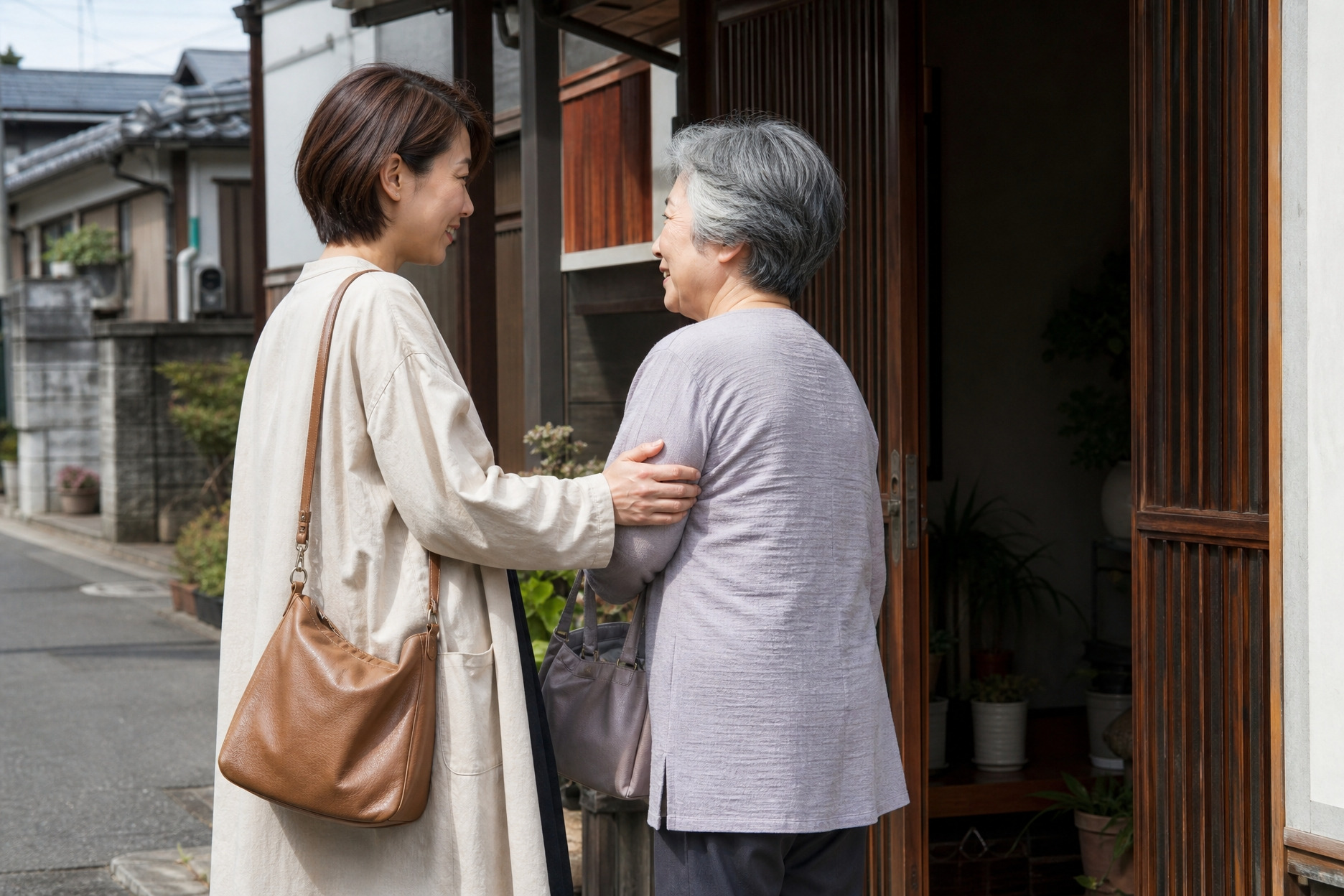 趣のある格子戸を備えた木造住宅の玄関先で、笑顔で言葉を交わす年配の女性と若い女性。実家周辺での土地探しや、家族との温かい繋がりを感じさせる様子です。