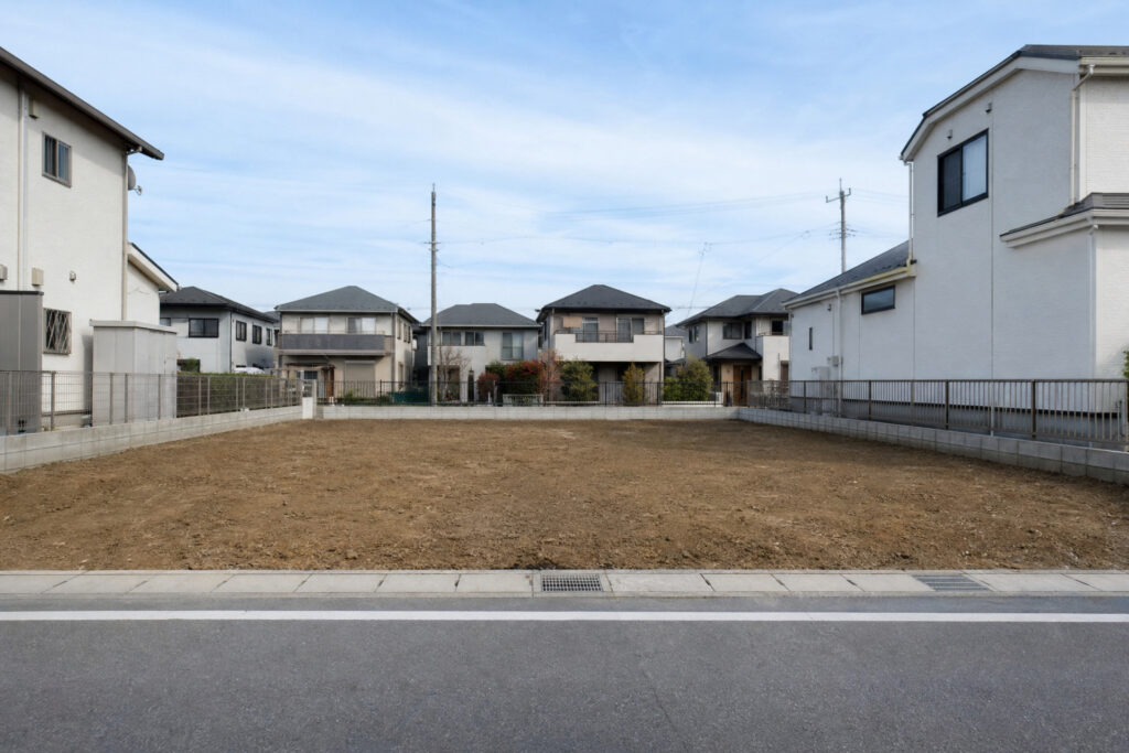 周囲に戸建て住宅が立ち並ぶ、きれいに整地された住宅街の更地。これから家づくりが始まる分譲地・建築予定地です。