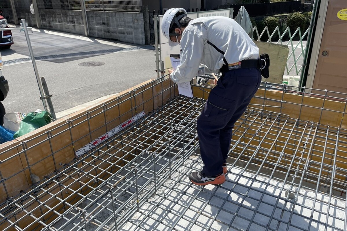 基礎工事の配筋検査。建物の荷重を支える重要な鉄筋が、図面通りに正しく配置されているか、第三者機関による厳しいチェック。