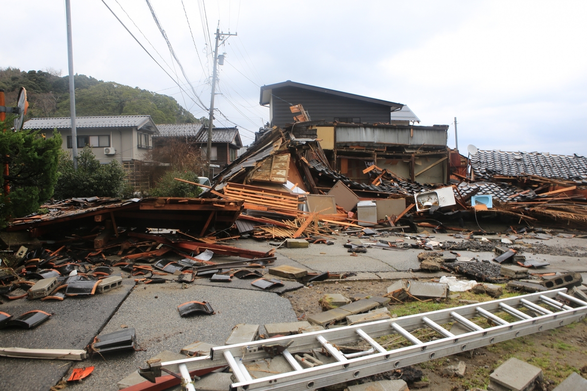 大地震の激しい揺れによって建物が倒壊し、瓦屋根や木材などの建材が道路にまで散乱している、木造住宅の甚大な被害状況。