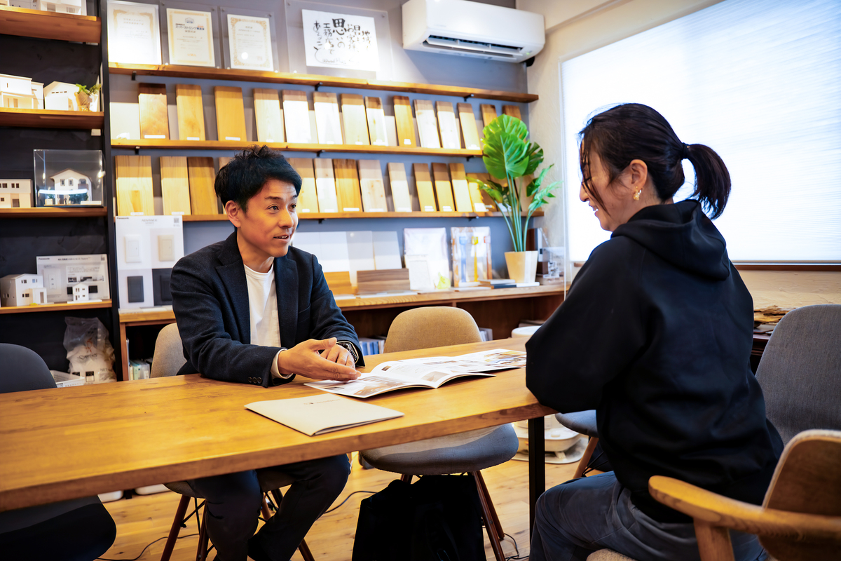 豊富な木製サンプルが並ぶショールームで、家づくりの打ち合わせを行うスタッフとお客様