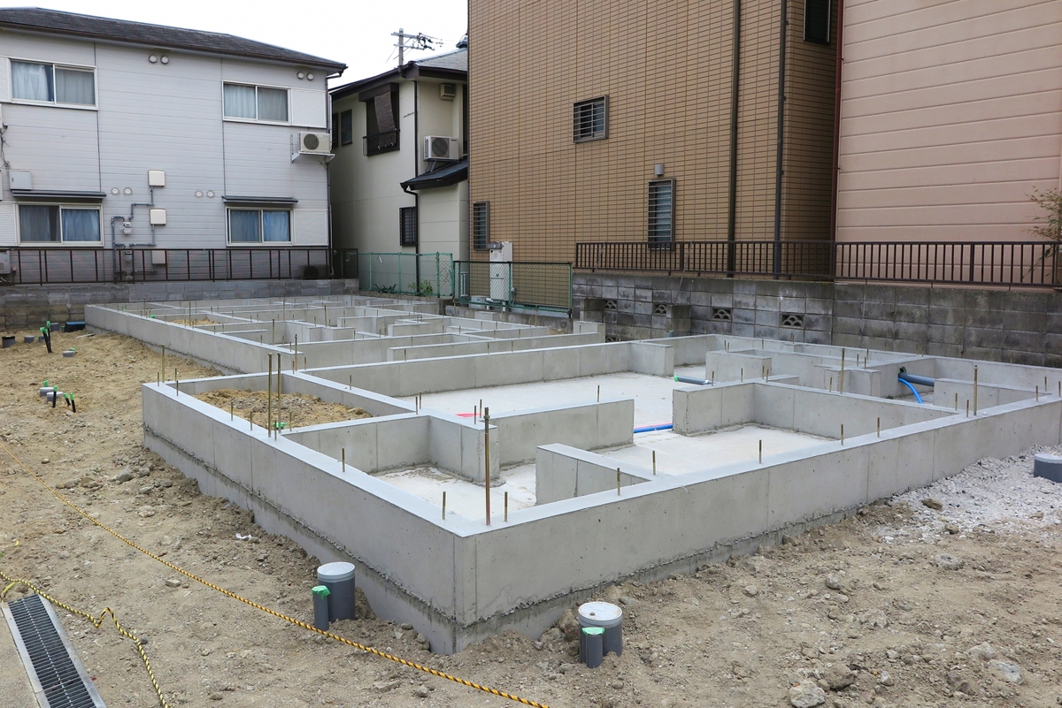 住宅建築現場におけるコンクリート基礎工事の様子。アンカーボルトや給排水用の配管スリーブが適切に施工されています。