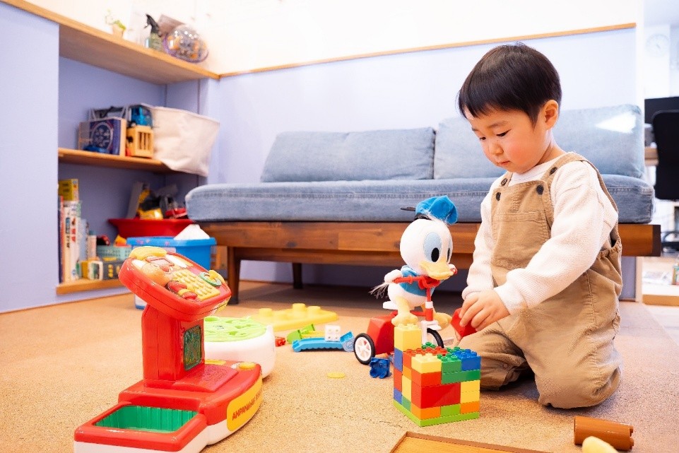 キッズスペースのカーペットの上で、カラフルなブロックやレジのおもちゃで夢中になって遊ぶ男の子