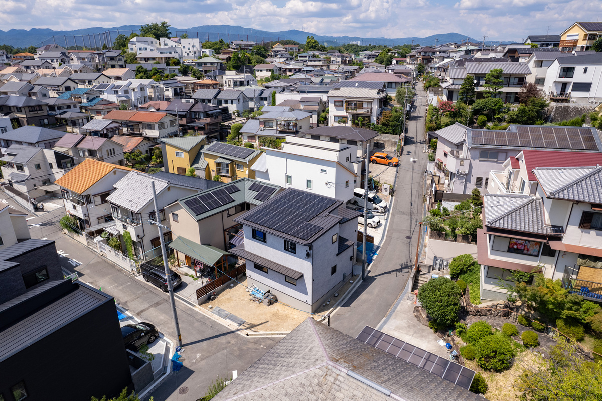 太陽光パネルを搭載した切妻屋根の注文住宅が立ち並ぶ、見晴らしの良い閑静な高槻市の住宅街の鳥瞰風景