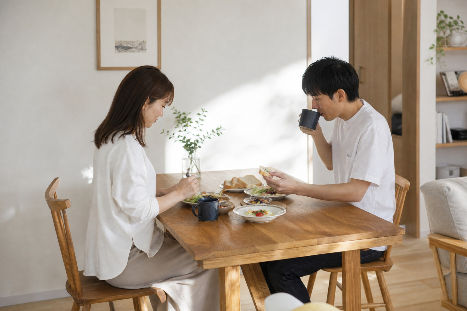 自然光が差し込む明るいダイニングで、無垢材のテーブルを囲んで食事をとる夫婦。ナチュラルテイストの温かみのある室内です。