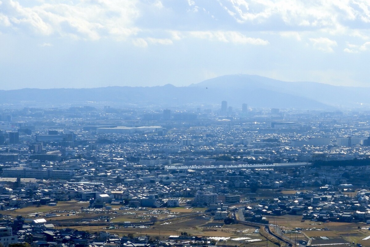 豊かな自然の山並みを背景に、住宅街が広がる市街地のパノラマ風景。土地探しの参考となる周辺環境の様子です。