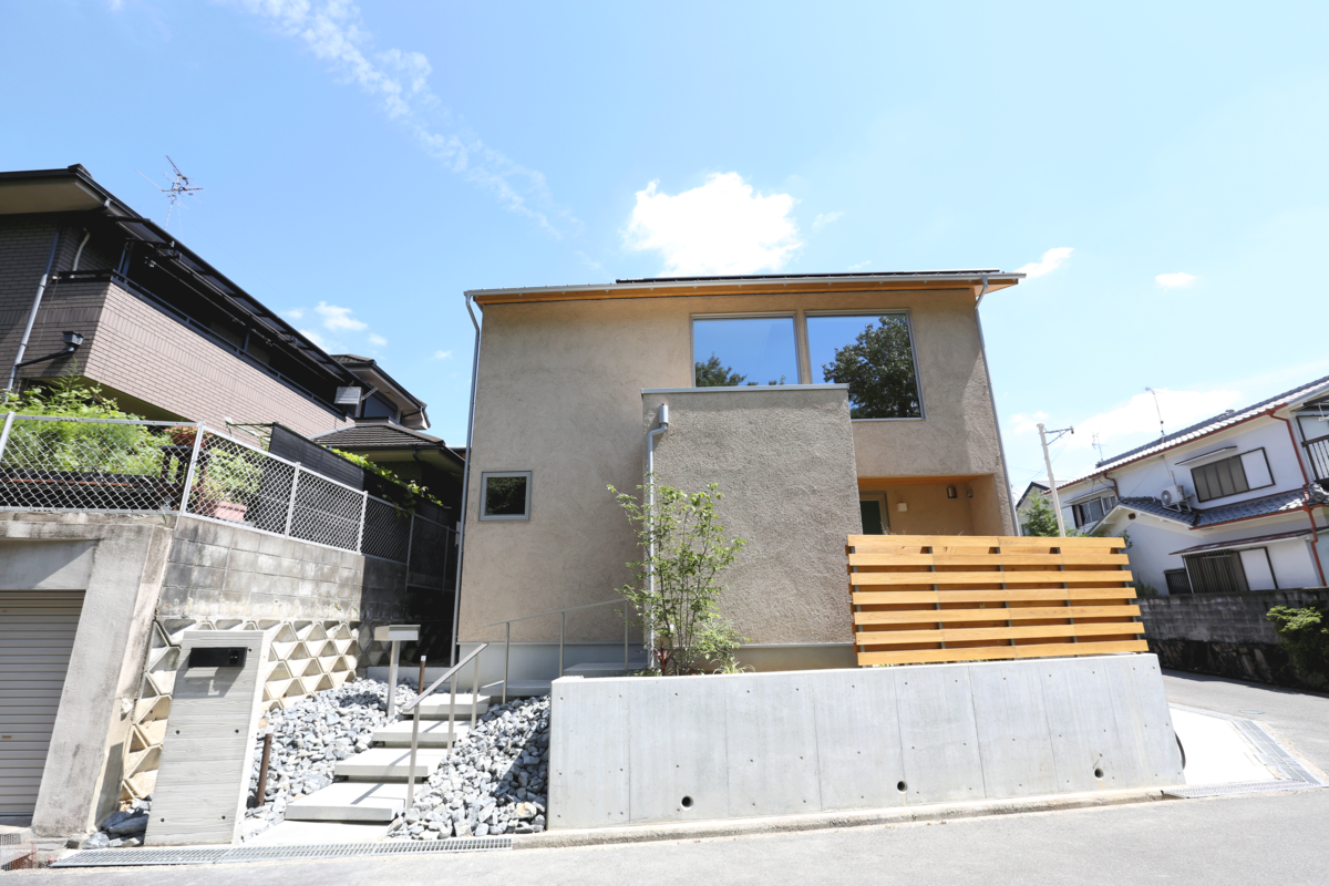 左官仕上げの塗り壁と木製フェンスが温もりを感じさせる、スタイリッシュな戸建て住宅の外観