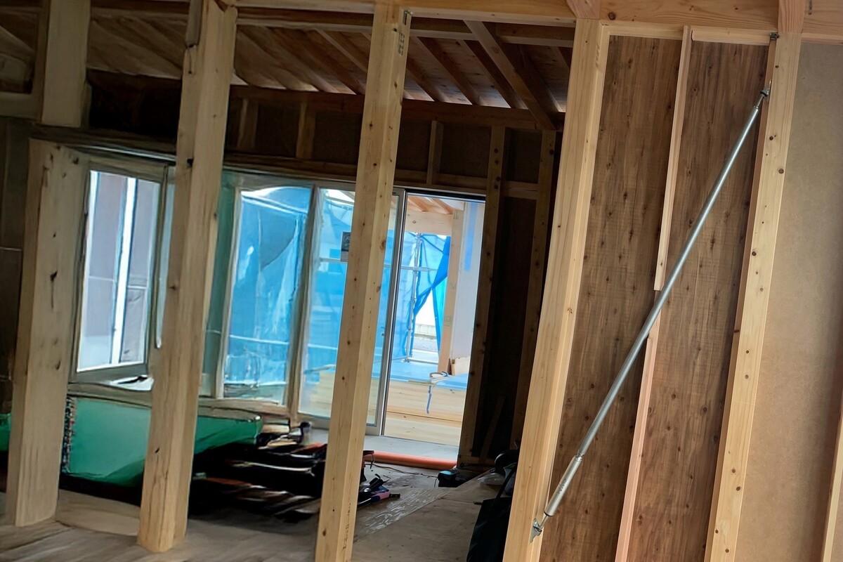 建築中の木造住宅の内部で、地震の揺れを吸収して建物を守るための金属製の制震ダンパーが柱と梁の間に斜めに施工されている様子。
