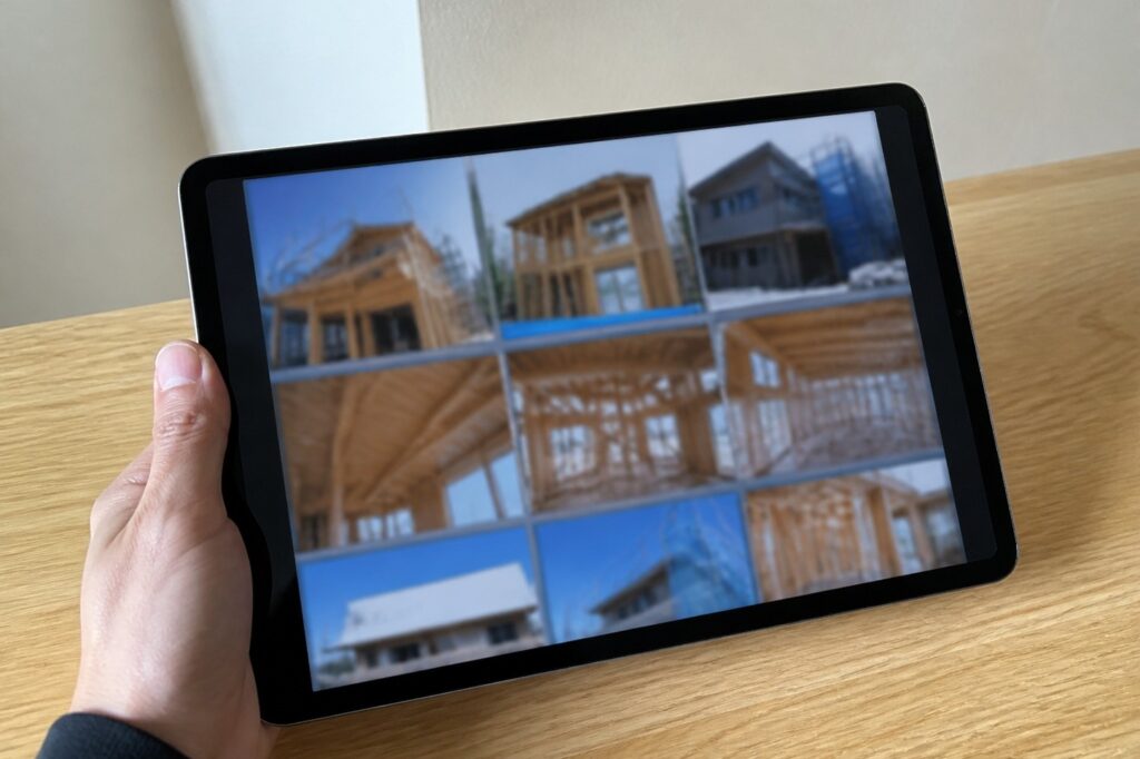 タブレット端末に表示された、住宅の骨組みや上棟時など複数の施工現場の記録。木造建築の構造や工事の進捗状況が確認できます。