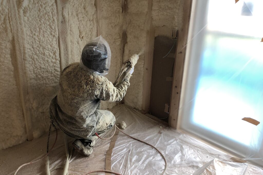 高気密・高断熱を実現するため、建築中の木造住宅の壁面に断熱材を吹き付けて施工している作業の様子。