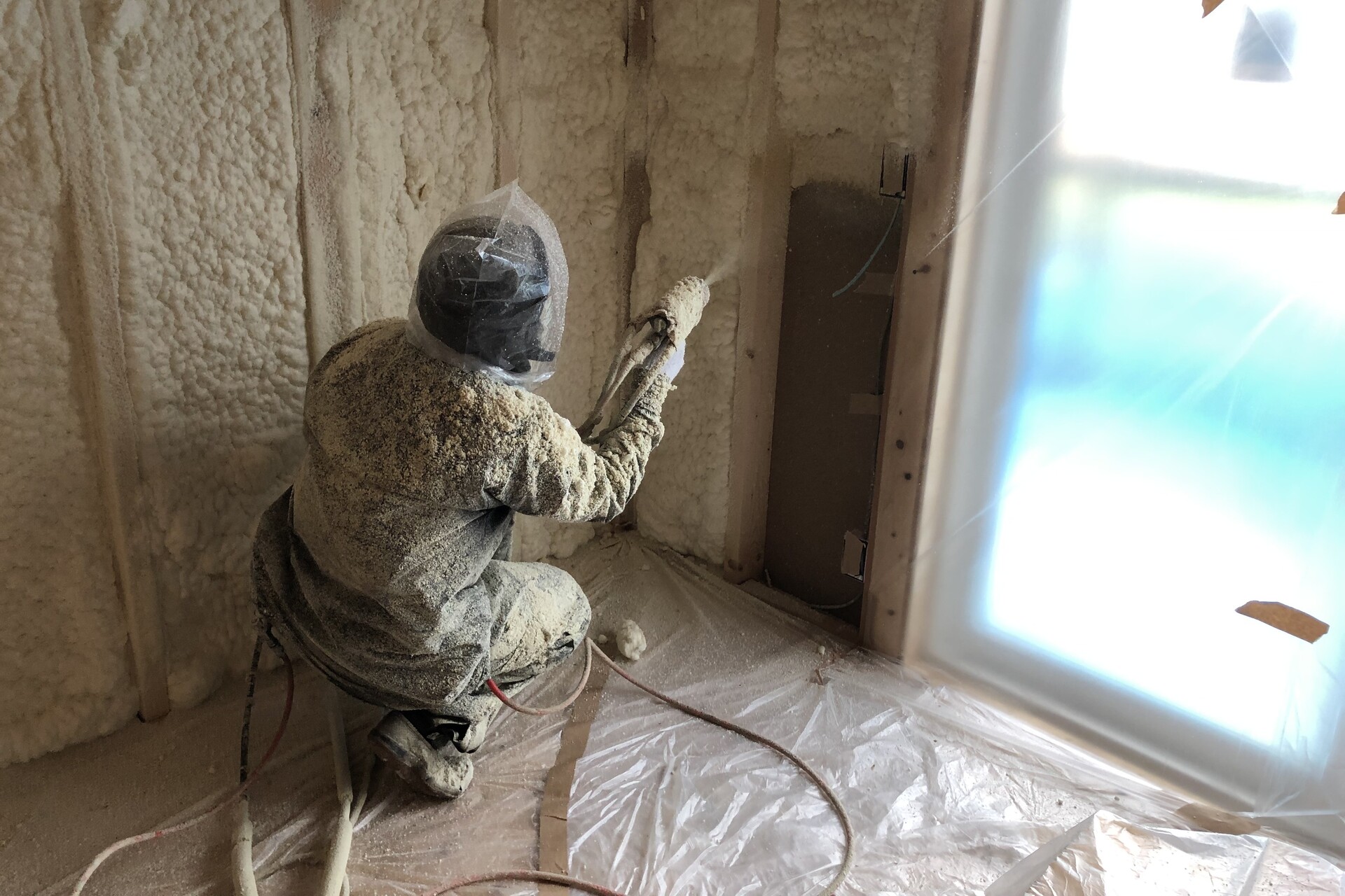 高気密・高断熱を実現するため、建築中の木造住宅の壁面に断熱材を吹き付けて施工している作業の様子。