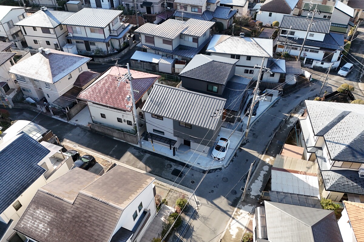 切妻屋根や片流れ屋根など、様々な形状の戸建て住宅が密集して立ち並ぶ、閑静な住宅街の俯瞰風景。