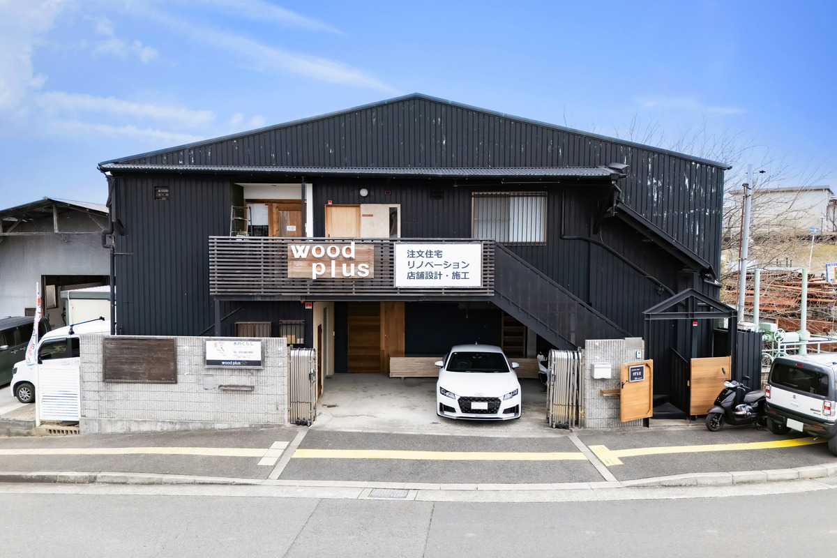 黒い外壁に「wood plus」のロゴサインが掲げられた、注文住宅やリノベーションを手がける工務店のオフィス外観。